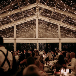 Party Hire Melbourne - A beautifully decorated wedding reception under a clear tent adorned with twinkling lights, showcasing an elegant atmosphere.