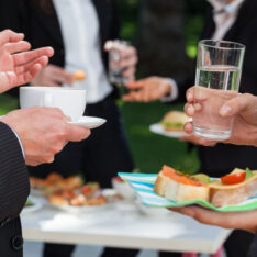 Two people holding drinks at corporate event outdoors