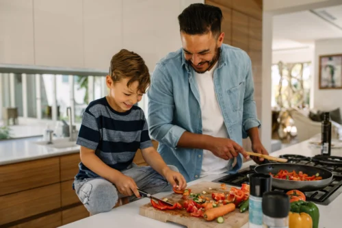 Father and young son cooking together in the kitchen as a fun activity.