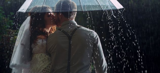 newlyweds kissing under umbrella